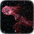 Image of IC 1396 taken by the Spitzer Space Telescope in the near-mid range of infrared. It has a pink cloud with bright blue spots of light over it and a black background.